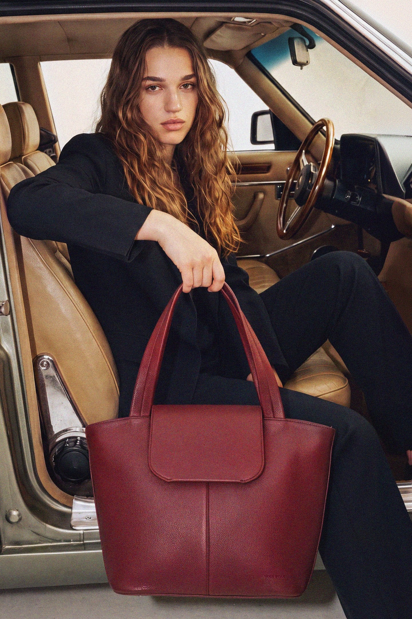 Woman in a vintage car with the Muse Bag in Burgundy