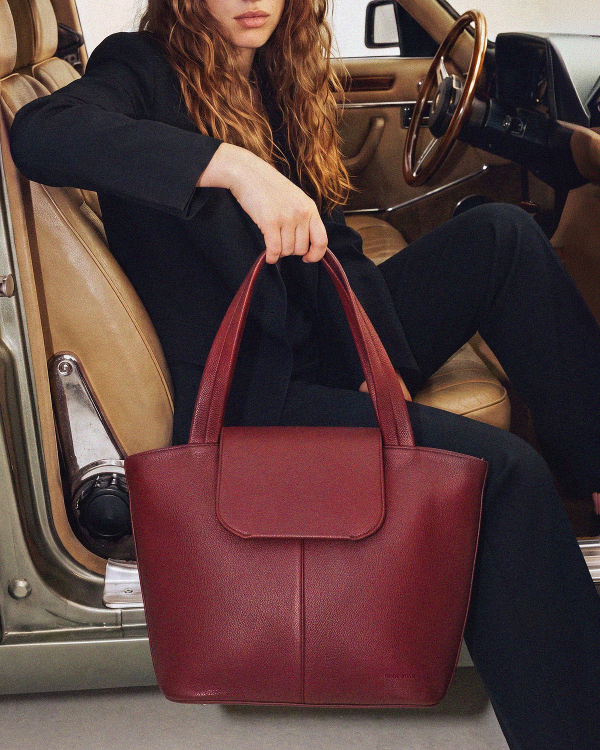 Woman leaving a hotel carrying the Muse Bag in Jet Black